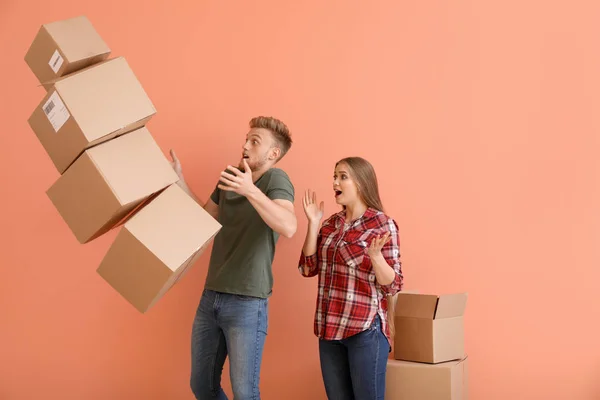 Jeune couple tombant boîtes en carton sur fond de couleur — Photo