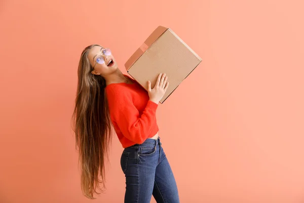 Młoda kobieta z kartonowym pudełkiem na tle koloru — Zdjęcie stockowe