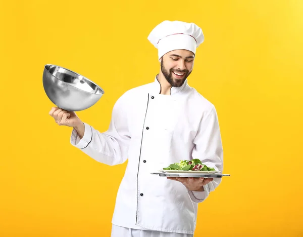 Knappe mannelijke chef-kok met salade op kleur achtergrond — Stockfoto