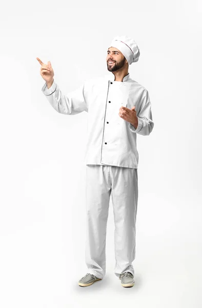 Knappe mannelijke chef-kok wijzend naar iets op witte achtergrond — Stockfoto