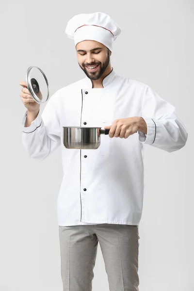 Pohledný mužský kuchař s hrncem na bílém pozadí — Stock fotografie