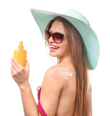 Beyaz arka plana karşı güneş koruma kremi uygulayarak güzel genç kadın