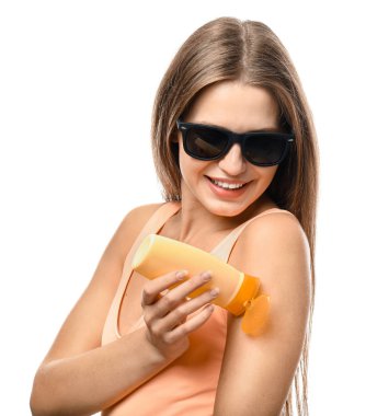 Beyaz arka plana karşı güneş koruma kremi uygulayarak güzel genç kadın