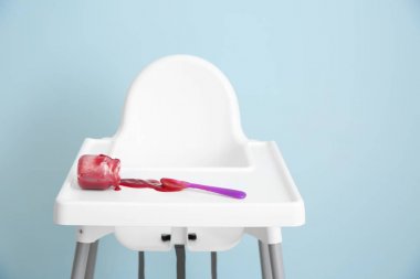 Gri arka plana karşı yüksek sandalyeye lezzetli bebek maması ile kavanoz overturned