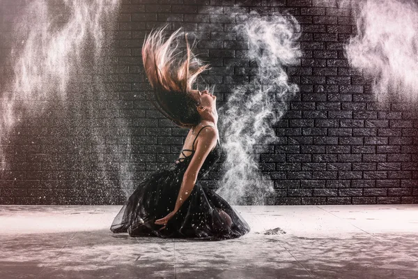 Όμορφη νεαρή μπαλαρίνα χορεύει με σκόνη εναντίον σκούρο τοίχο — Φωτογραφία Αρχείου