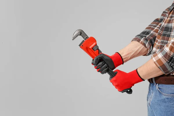 Plumber with pipe wrench on grey background — Stock Photo, Image