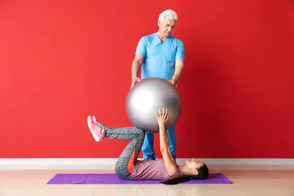 Mature physiotherapist working with young Asian woman in clinic — Stock Photo, Image