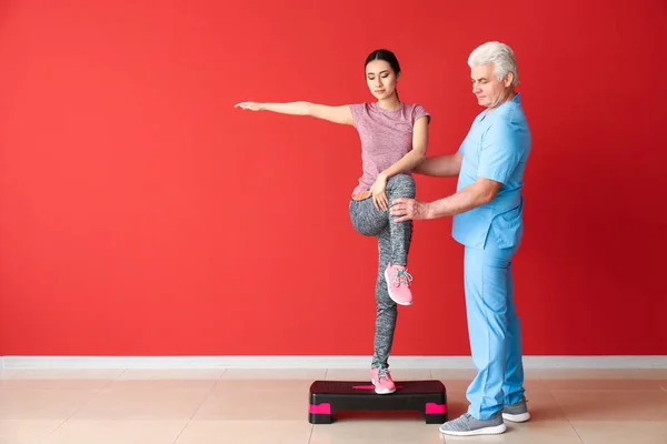 Mature physiotherapist working with young Asian woman in clinic — Stock Photo, Image