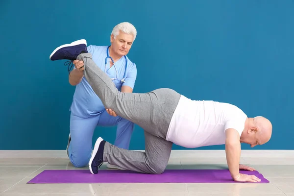 Mature physiotherapist working with senior man in clinic — Stock Photo, Image