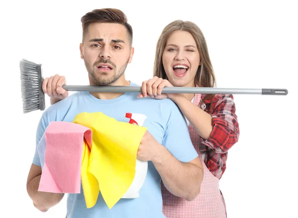 Esposa feliz e marido triste com suprimentos de limpeza no fundo branco — Fotografia de Stock