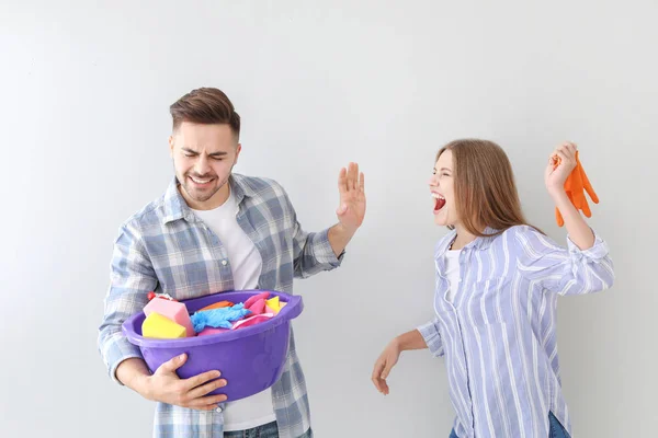 Arg fru skällde sin man med rengörings materiel på grå bakgrund — Stockfoto