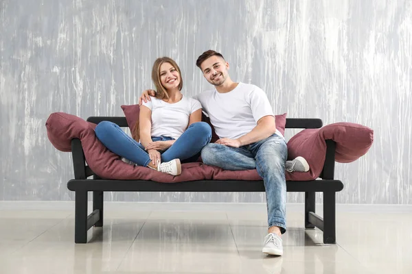 Szczęśliwa Młoda para spoczywających razem na kanapie w pobliżu grunge Wall — Zdjęcie stockowe