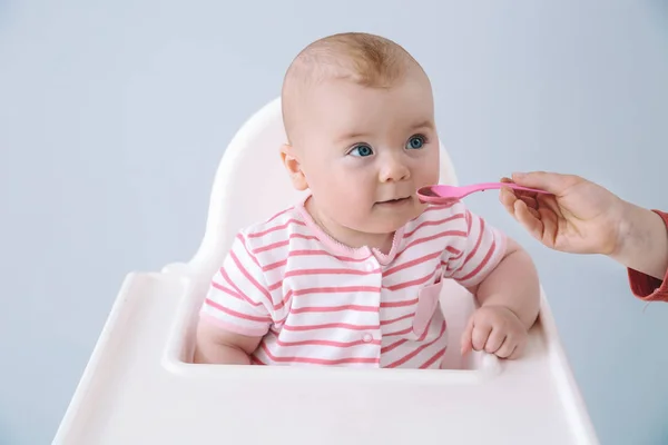 Lindo bebé comiendo comida sabrosa sobre fondo gris — Foto de Stock