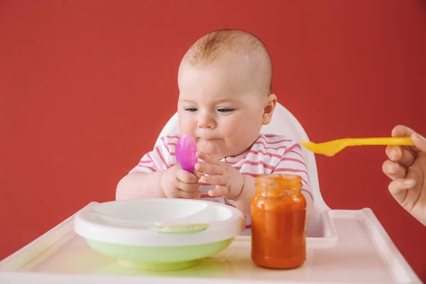 Lindo bebé comiendo comida en el fondo de color — Foto de Stock