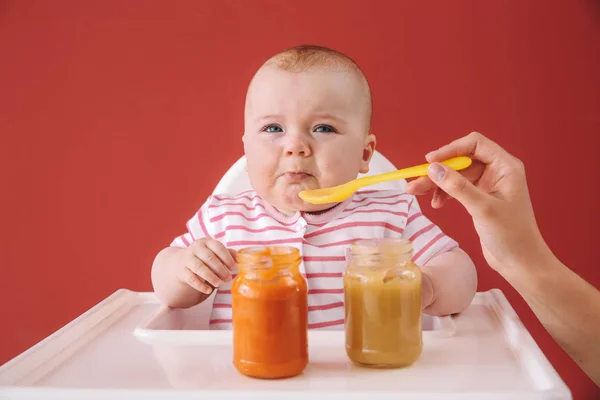 Lindo bebé comiendo comida en el fondo de color — Foto de Stock