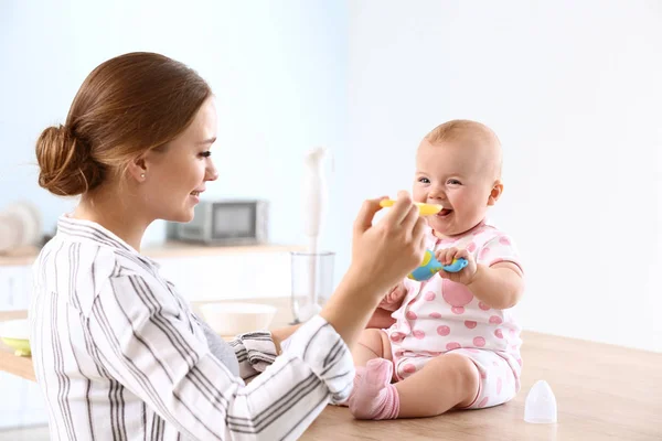 Matka krmí své malé děťátko doma v kuchyni — Stock fotografie