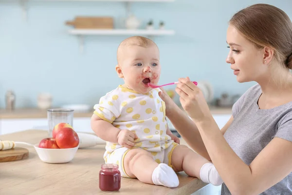 Mother feeding her little baby in kitchen at home — Stock Photo, Image
