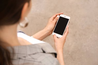 Dışarıda cep telefonu olan genç bir kadın.