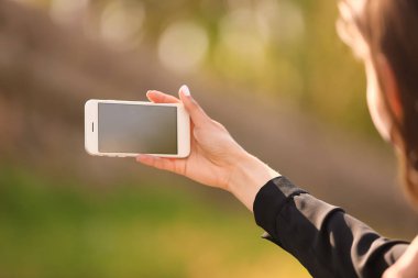 Cep telefonu ile genç kadın açık havada fotoğraf çekmek