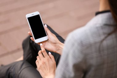 Dışarıda cep telefonu olan genç bir kadın.