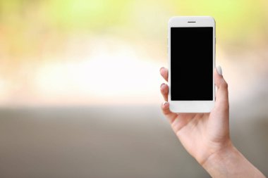 Dışarıda cep telefonu olan genç bir kadın.