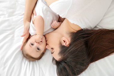 Yatakta yatarken sevimli küçük bebek ile mutlu anne