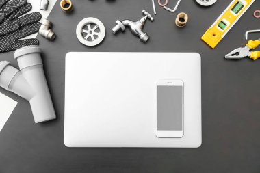 Karanlık arka planda modern dizüstü bilgisayar, cep telefonu ve tesisatçı öğeleri