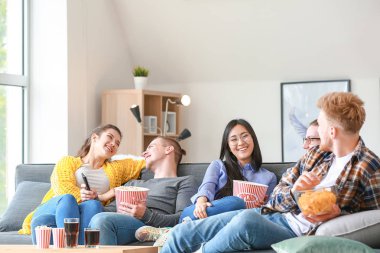 Arkadaşlar evde televizyon izliyor.