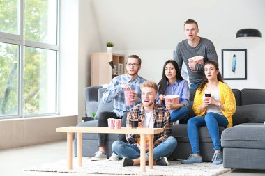 Arkadaşlar evde televizyon izliyor.