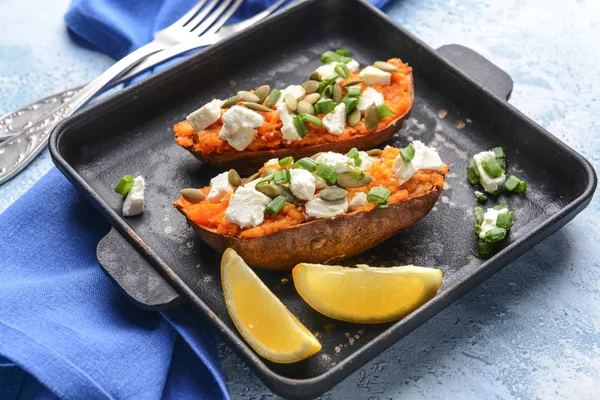 Baked sweet potato with cheese and arugula in frying pan