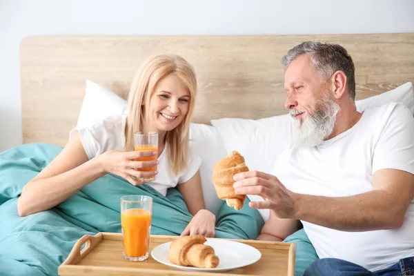 Feliz casal idoso tomando café da manhã na cama — Fotografia de Stock