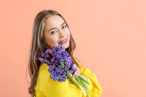 色の背景にヒヤシンスの花を持つ美しい若い女性 — ストック写真