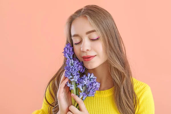 Vacker ung kvinna med hyacint blommor på färg bakgrund — Stockfoto