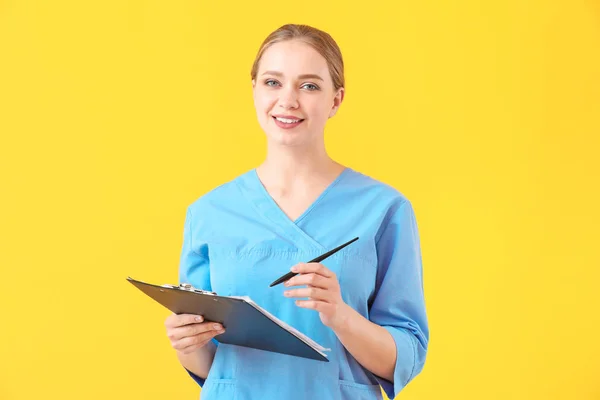 Młoda asystentka medyczna z dokumentami na tle koloru — Zdjęcie stockowe