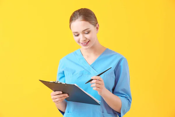 Young medical assistant with documents on color background — Stock Photo, Image