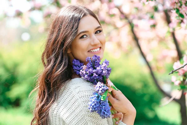 Beautiful young woman with hyacinth flowers outdoors — Stockfoto