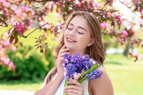 Beautiful young woman with hyacinth flowers outdoors — Zdjęcie stockowe