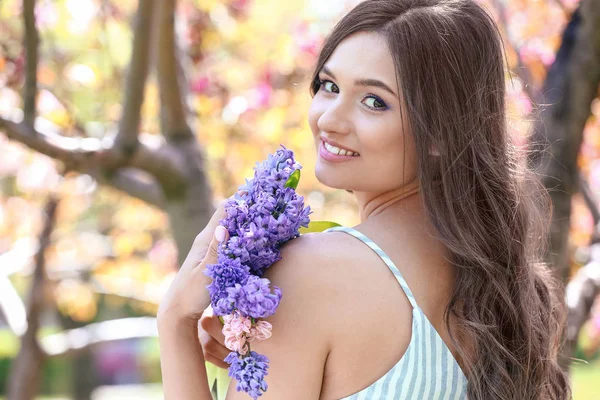 Beautiful young woman with hyacinth flowers outdoors — Stockfoto