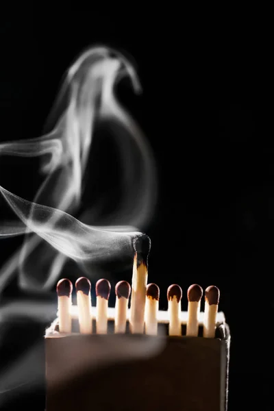 Box with matches and smoke on dark background