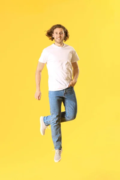 Jumping young man in jeans on color background — Stock Photo, Image