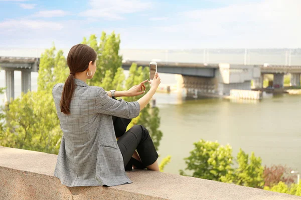 Ung kvinna med mobil telefon ta foto utomhus — Stockfoto