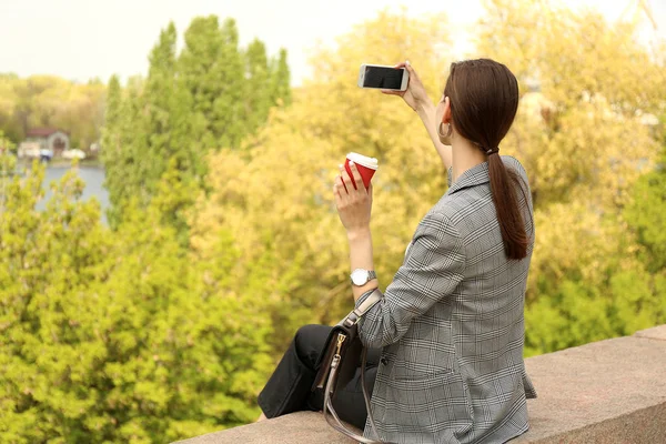 Ung kvinna med mobil telefon ta foto utomhus — Stockfoto