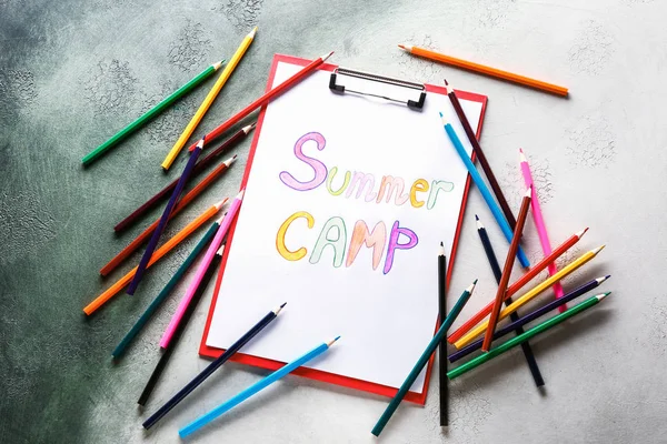 Sheet of paper with text SUMMER CAMP and pencils on color background — Stock Photo, Image