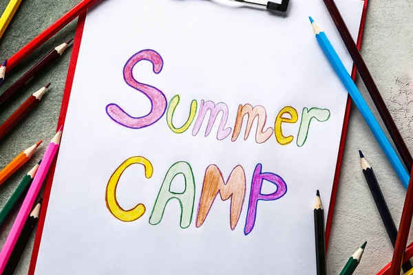 Sheet of paper with text SUMMER CAMP and pencils on grey background — Stock Photo, Image