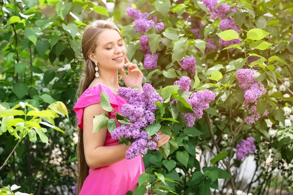 아름 다운 젊은 여자 근처 꽃이 만발한 라일락 부시 야외에서 — 스톡 사진