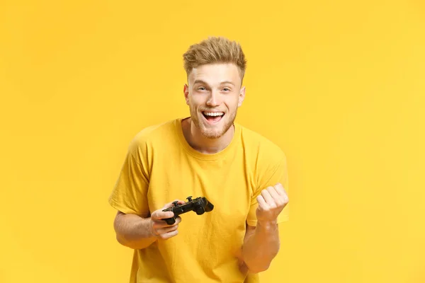 Portrait of happy young man playing video games on color background — Stock Photo, Image