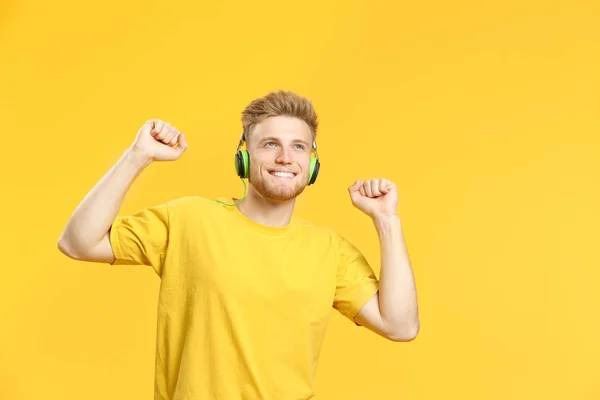 Portrait of happy young man listening to music on color background — Stock Photo, Image
