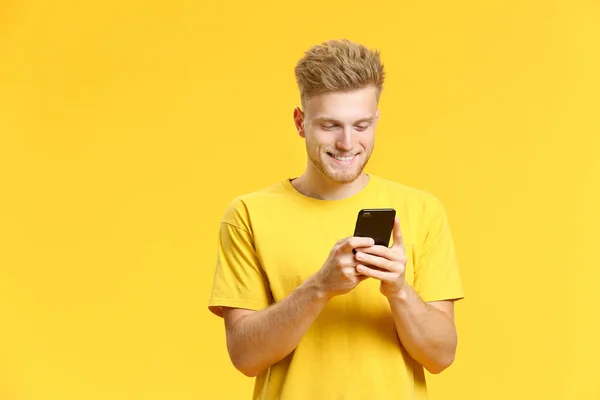 Retrato de joven feliz con teléfono móvil sobre fondo de color —  Fotos de Stock
