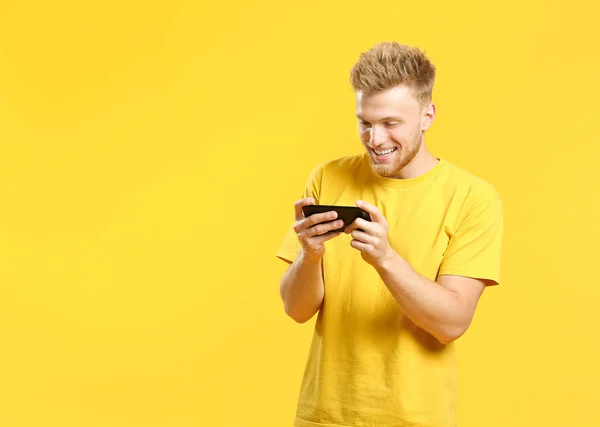 Retrato de joven feliz con teléfono móvil sobre fondo de color —  Fotos de Stock