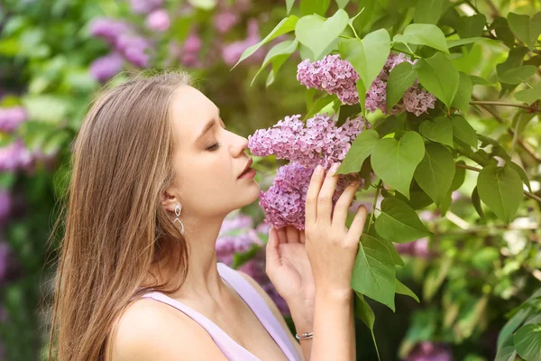 Vacker ung kvinna nära blommande lila buske utomhus — Stockfoto